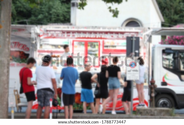 Blurred background of Food truck on wheels.The\
traditional Italian cuisine on the road. Food served by  truck\
around the streets.With many\
customers