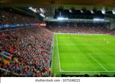 Blurred Background Of Football Players Playing And Soccer Fans In Match Day On Beautiful Green Field With Sport Light At The Stadium.Sports,Athlete,People Concept.Anfield,Liverpool,UK