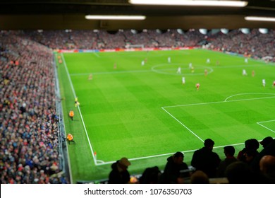 Blurred background of football players playing and soccer fans in match day on beautiful green field with sport light at the stadium. Sports,Athlete,People Concept.Anfield,Mercyside,Liverpool,UK.