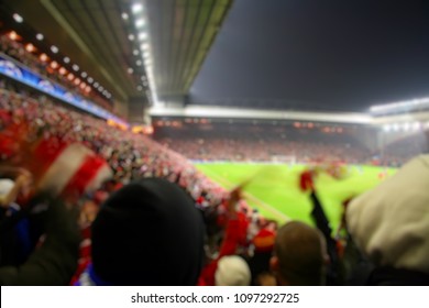 Blurred background of football players playing and soccer fans in match day on beautiful green field with sport light at the stadium.Sports,Athlete,People Concept.Anfield,Liverpool.European Night.