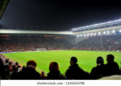 Blurred background of football players playing and soccer fans in match day on beautiful green field with sport light at the stadium. Sports,Athlete,People Concept.Anfield.Liverpool
