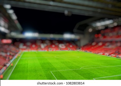 Blurred background of football stadium and soccer fans in match day on beautiful green field with sport light at the stadium.Sports,Athlete,People Concept.Mercy side,Anfield,Liverpool. 