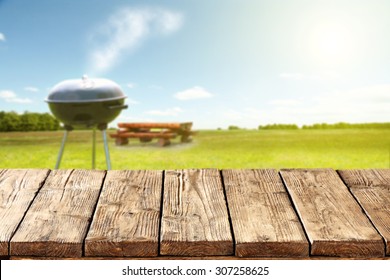 blurred background of green grass and blue sky and grill with table place of space for your decoration 