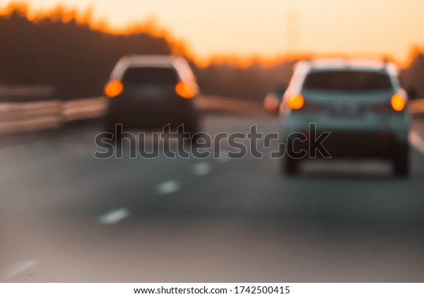 Blurred background\
with highway and cars at sunset, bokeh lights. Bokeh cars on\
freeway at sunset blurred background for design. Multiple vehicles\
on road blurred with bokeh.\
