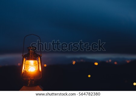 Blurred background image of a glowing lantern against dark night time mountains with lights