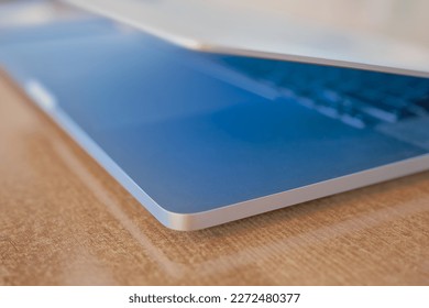 Blurred background of a laptop on a table in a coworking space, the screen glows blue, splash screen or background for a banner about networking or programming