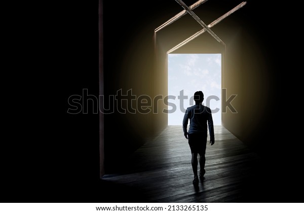 Blurred background man get out of the darkness,\
walking trough an open door. man in silhouette walking trough\
different shaped door. way of survival. Solve problems. solution.\
choice. tunnel. light