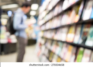 Blurred Background Of Man Read A Book At Bookshelves In Book Store. Student Research Knowledge In Textbook In Library Of University