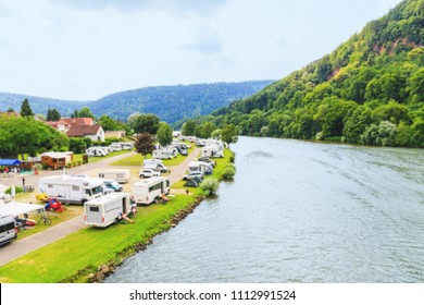 Blurred background with Modern camp site on  river Neckar, Germany. Family vacation in caravan park. Caravan camping on the summer beach. Traveling Europe in motorhome. 