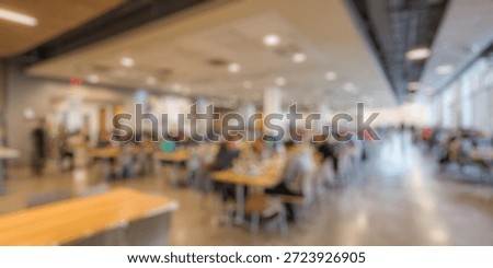 Blurred Background of Modern dining hall filled with students enjoying meals in a spacious, bright cafeteria setting, featuring communal tables and large windows allowing natural light.