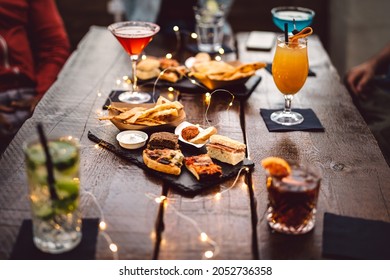 Blurred background of multicolored drinks and minimal food - Happy hour concept with fancy cocktails and tasty appetizers served at rooftop lounge prive - Warm vintage filter on shallow depth of field