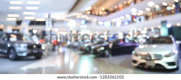 Blurred background of\
new cars displayed in luxury showroom with light bokeh in motor\
show event, panorama
