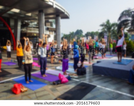 Blurred background of people playing yoga outdoor with natural color tone tuned. Unrecognized people.