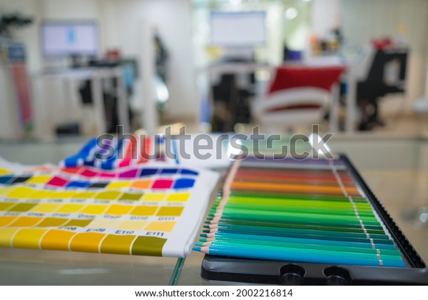 A blurred background photo of the inside of\
printing room. Color Palette Guide. Sample Colors Catalog.\
Multicolored bright background. RGB. CMYK. Printing sublimation\
house. Selective focus.