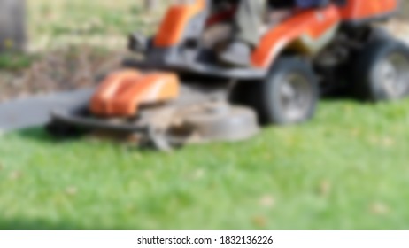 Blurred Background. Professional Lawn Mowing Machine. Summer And Autumn Season Sunny Lawn Mow In The Garden