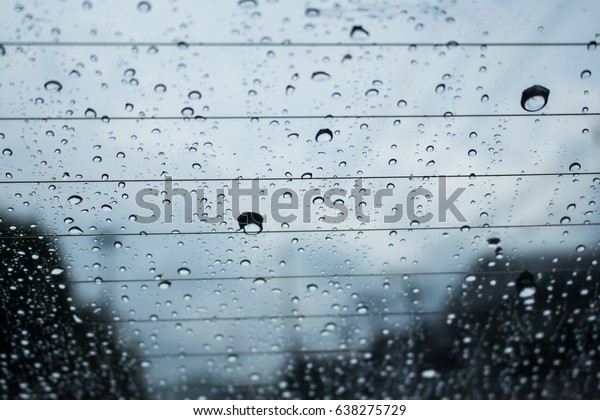 Blurred background with rain drop on car\
window . Driving car in the rain on wet\
road