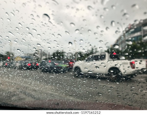 Blurred background\
with rain drops on glass surface and cars on the road. Road view\
through car window blurry with heavy rain, driving in rain, rainy\
weather. Selective\
focus