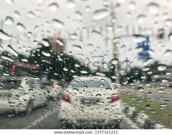 Blurred background\
with rain drops on glass surface and cars on the road. Road view\
through car window blurry with heavy rain, driving in rain, rainy\
weather. Selective\
focus