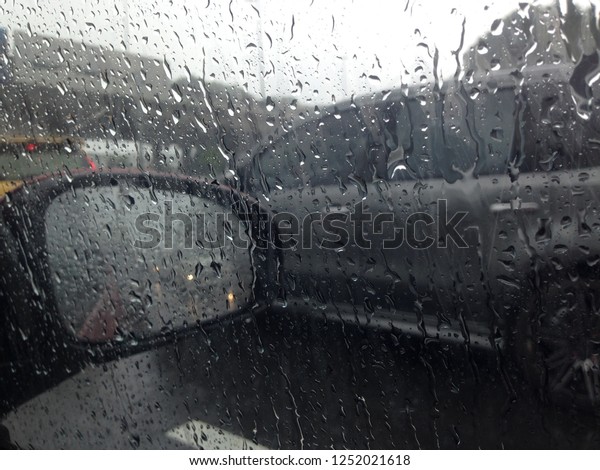 Blurred\
background with rain drops on glass car on the road, road view\
through car window blurry with heavy rain, driving in rain, rainy\
weather. Water drop rain on road blur\
background.