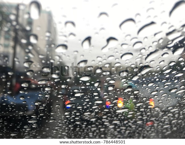 Blurred background,\
raindrop on the windshield, traffic in the city on a rainy day, car\
windshield view.