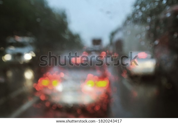 Blurred background with\
raindrops on glass and cars on the road. View of the road through\
the car window blurred by heavy rain. Out of focus, blur, artistic\
noise