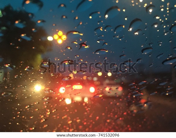 Blurred background,
raindrops on the windshield, street lights at night on a rainy day,
colorful bokeh.
