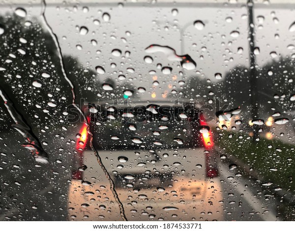 Blurred\
background with rains drop on glass and cars on the road. Road view\
through car window blurry with heavy rain, Driving in rain rainy\
weather. Water drop rain on road blur\
background.