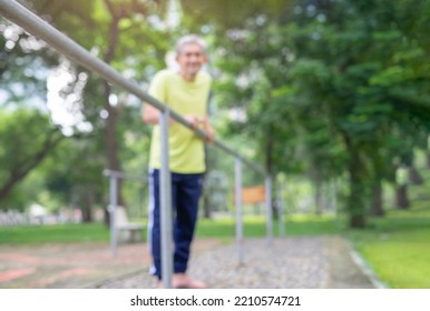 Blurred Background Of Senior Man With Bare Feet Try To Walking Himself In Rehab Equipment At Park,concept Older Adult After Chronic Illness Stroke,paralysis,disability, To Be Able Take Care Themselves