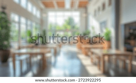 Blurred background of spacious and bright cafe interior featuring wooden tables and greenery, creating an inviting atmosphere perfect for socializing or working in a stylish setting.