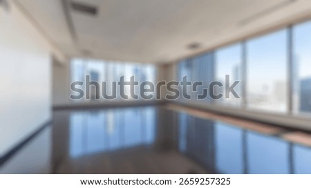 Blurred background of spacious empty office space featuring large panoramic windows with breathtaking city views, perfect for creative projects or corporate use in a modern urban setting.
