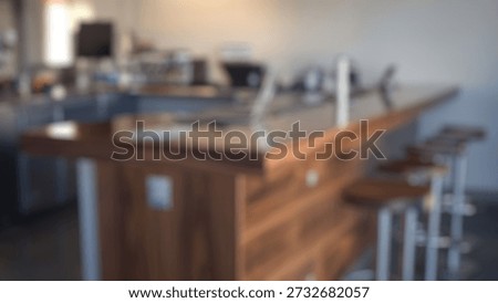 Blurred background of spacious kitchen bar interior with a sleek wood countertop and modern stainless steel accents, perfect for entertaining guests in a stylish environment.