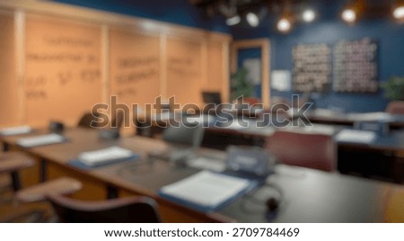 Blurred background of spacious office environment with empty desks ready for work, featuring paperwork, monitors, and wall-mounted schedules aimed at enhancing productivity and organization.