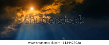blurred background, sun and rays on a dark background of thunderclouds. Horizontal banner.
