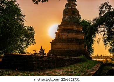 Blurred background of sunlight with old Buddha statue against evening sky light, beauty of ancient ruins in Ayutthaya of Thailand.
