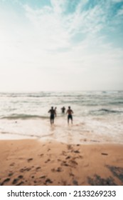 Blurred Background Of Three People Running On The Beach Towards The Sea During The Day Time