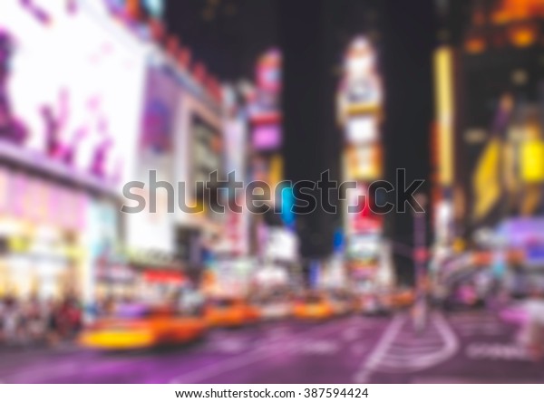 Blurred background Time Square New York\
City at night with taxi and bokeh neon city\
light.