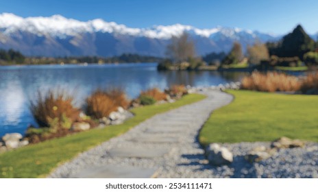 Blurred background of a tranquil landscaped view of a serene lake surrounded by majestic mountains, featuring a winding stone path and lush greenery, perfect for relaxation. - Powered by Shutterstock