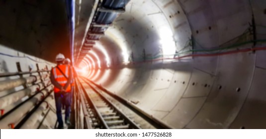 Blurred background of underground tunnel construction with light at the end of the tunnel.Transport pipeline by Tunnel Boring Machine for electric train subway with control engineer or security safety