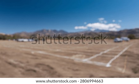 Blurred Background of Undeveloped Plot of Land with Ground Markings Set Against a Scenic Mountain Background in Bright Daylight