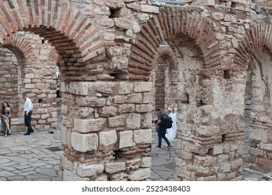 Blurred background. Wedding ceremony in old ruined fortress. Photo session, photographer with camera. Bride in white dress - Powered by Shutterstock