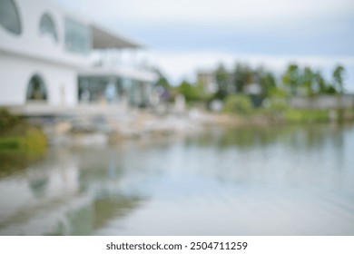 Blurred background of the white glass house is next to the lake, with the exterior of the building decorated in a garden with large trees. - Powered by Shutterstock