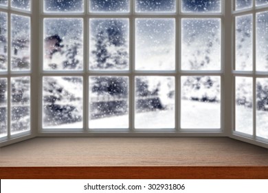 blurred background of window with winter landscape and dark brown furniture top 