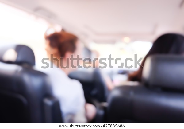 Blurred \
background of women with friend in\
car.