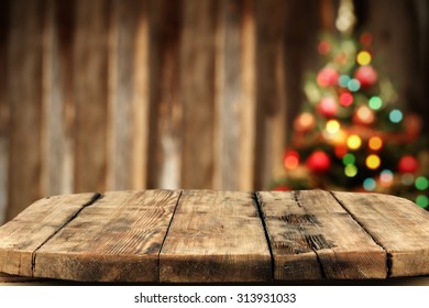 Blurred Background Of Xmas Tree Lights And Wall With Woorn Wooden Big Table 