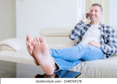 Blurred background of young man talking on a mobile phone while sitting on the couch. Shot at home
