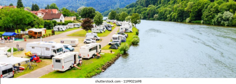Blurred banner background with Modern camp site on  river Neckar, Germany. Family vacation in german caravan park. Caravan camping on the summer beach. Traveling Europe in motorhome