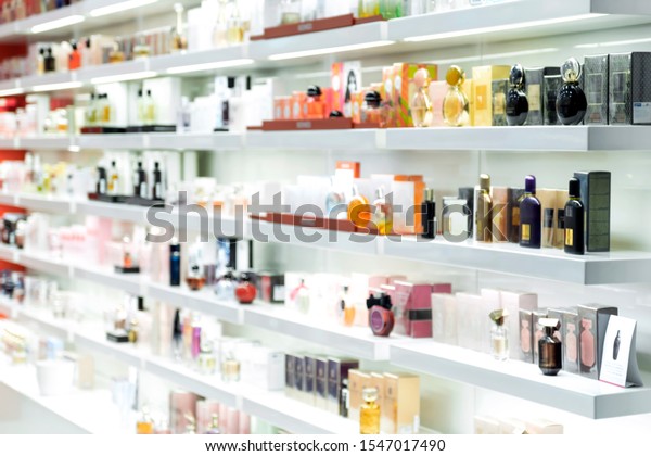 Blurred beautiful shop in shopping malls. Big sales on\
Black Friday for Christmas. The large perfumery shop of elite\
perfumery and cosmetics is washed out. Rack with shelves in a large\
drogeria 