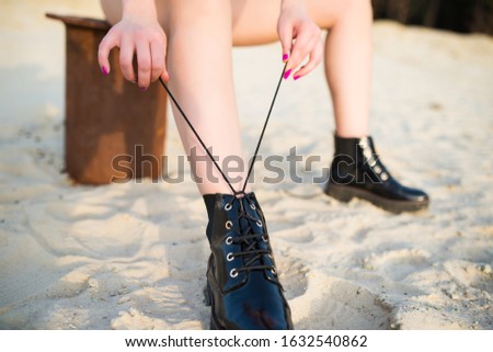 Blurred beautiful young girl tying shoelaces on leather shoes. Concept foot fetish and both fashion and style. Concept of clothes and accessories and shoes