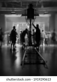 Blurred Behind The Scenes Of Music Video Shooting Production Crew Team Silhouette And Camera Equipment In Studio. Soft Focus. Black And White.