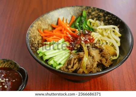 Blurred Bibimbap as Korean food in black textured bowl, wooden pattern background